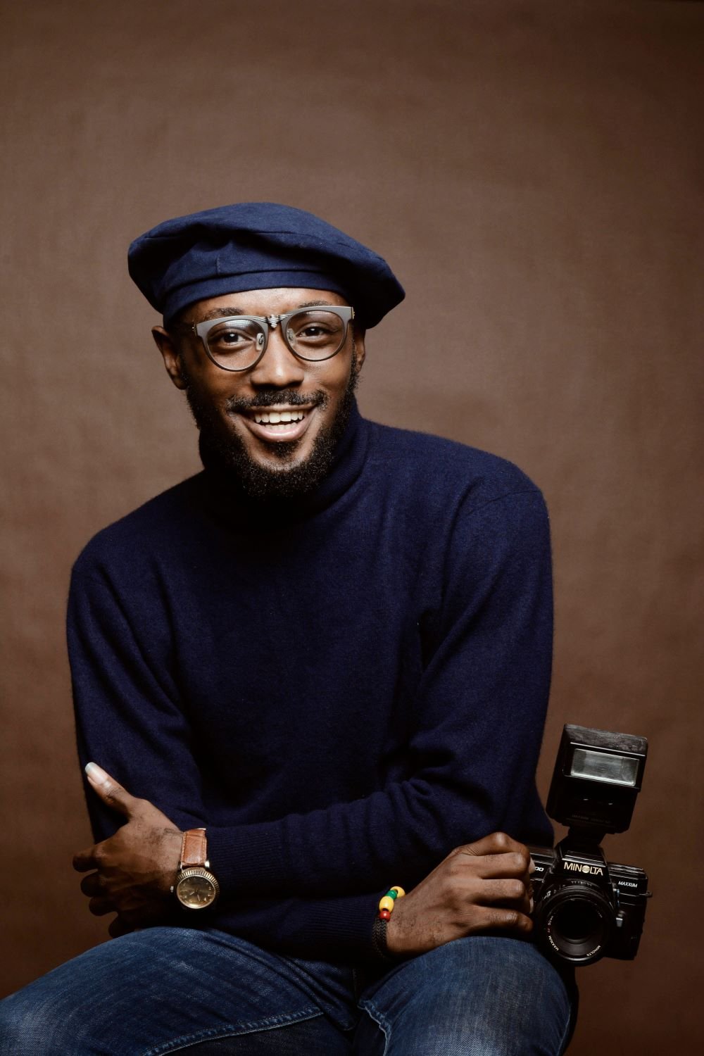 Portrait d’un homme souriant coiffé d’un béret, appareil photo à la main
